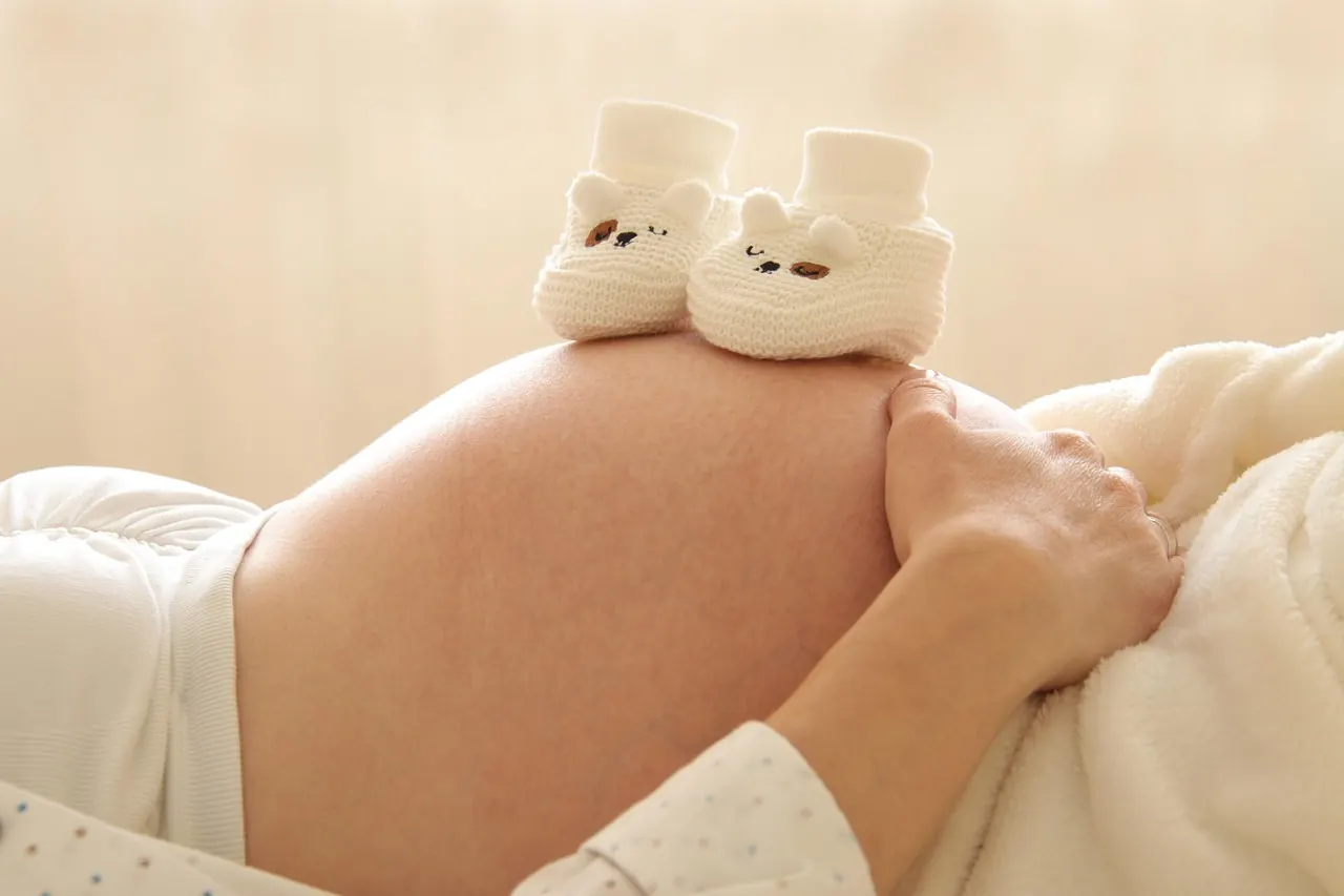 Đôi giày em bé đặt trên bụng bầu