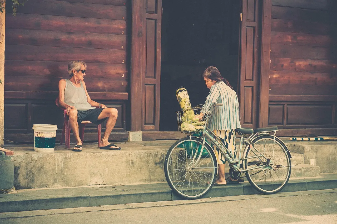 Người đàn ông dắt xe đạp qua dãy nhà cũ