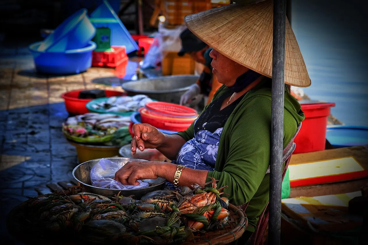 Người bán cá đội nón lá tại sạp chợ