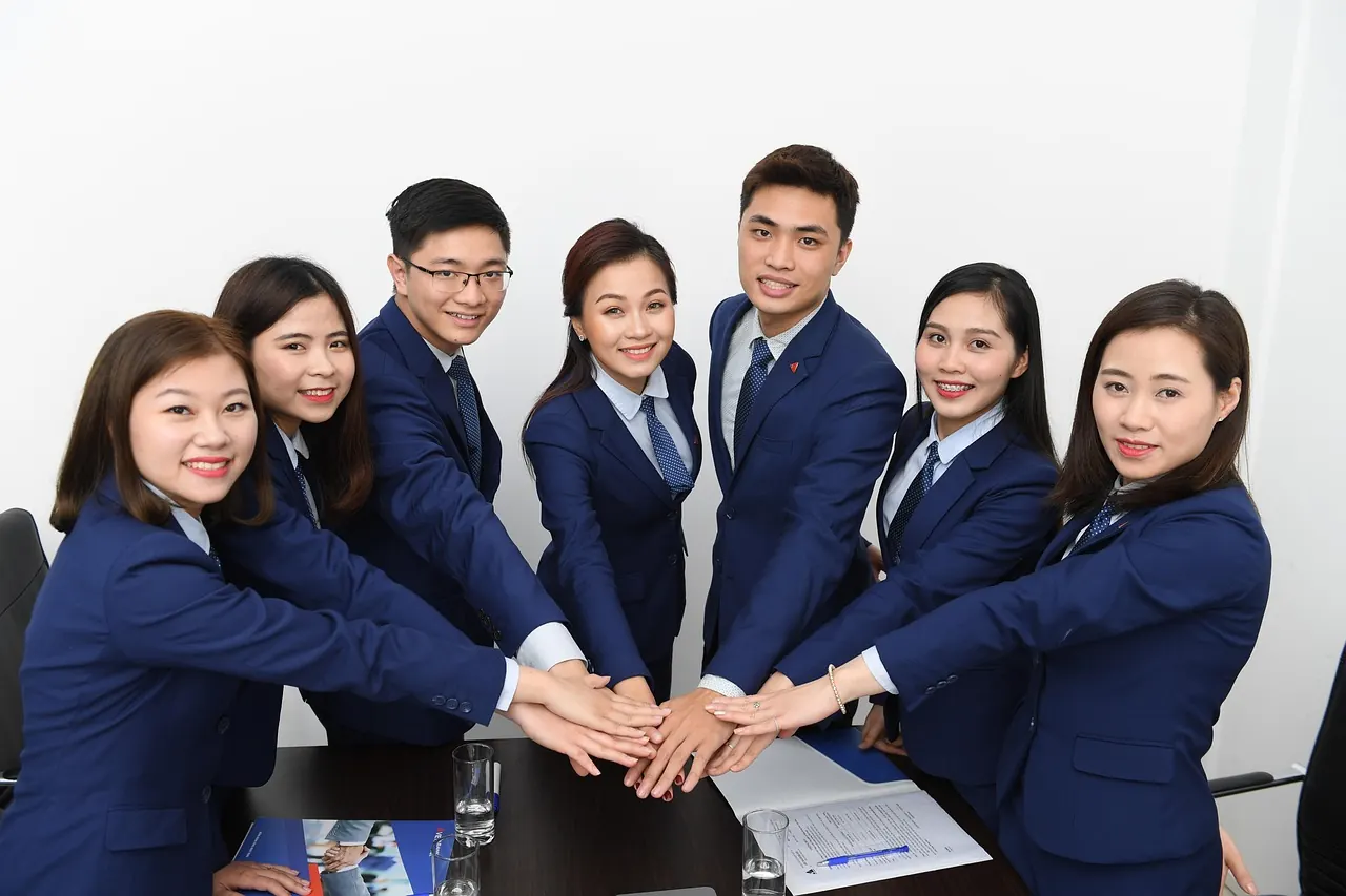 Nhóm nhân viên châu Á mặc đồng phục chụm tay cổ vũ