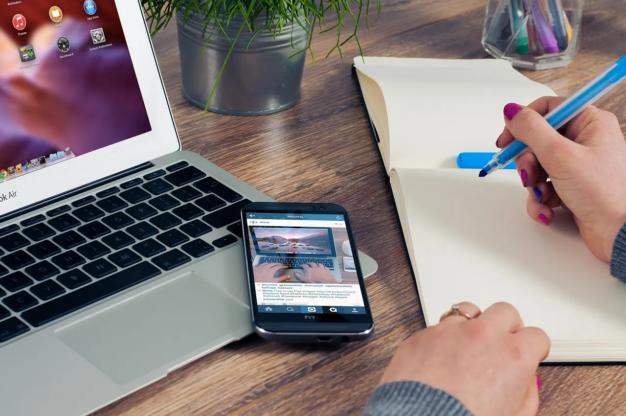 Bàn tay ghi chép bên laptop và điện thoại