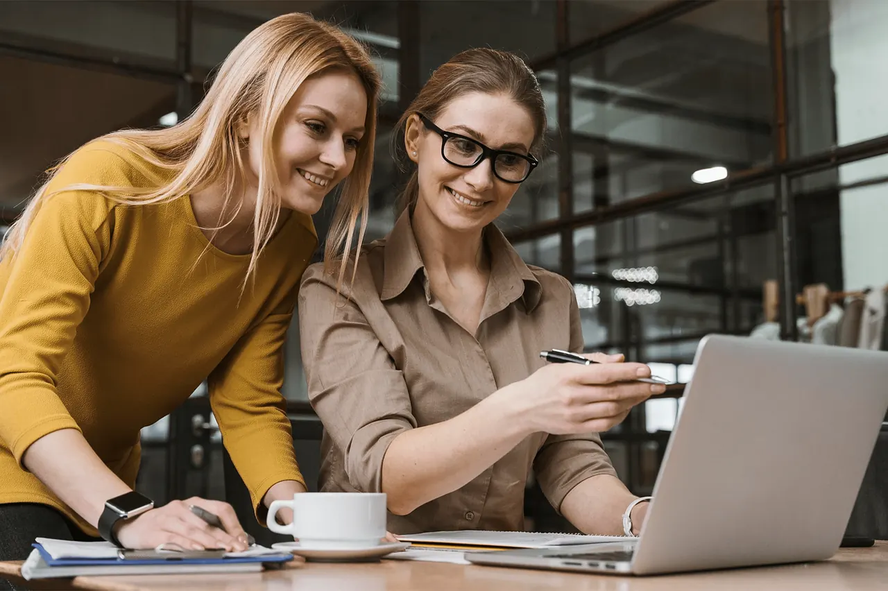 Hai đồng nghiệp nữ cùng xem laptop trong văn phòng