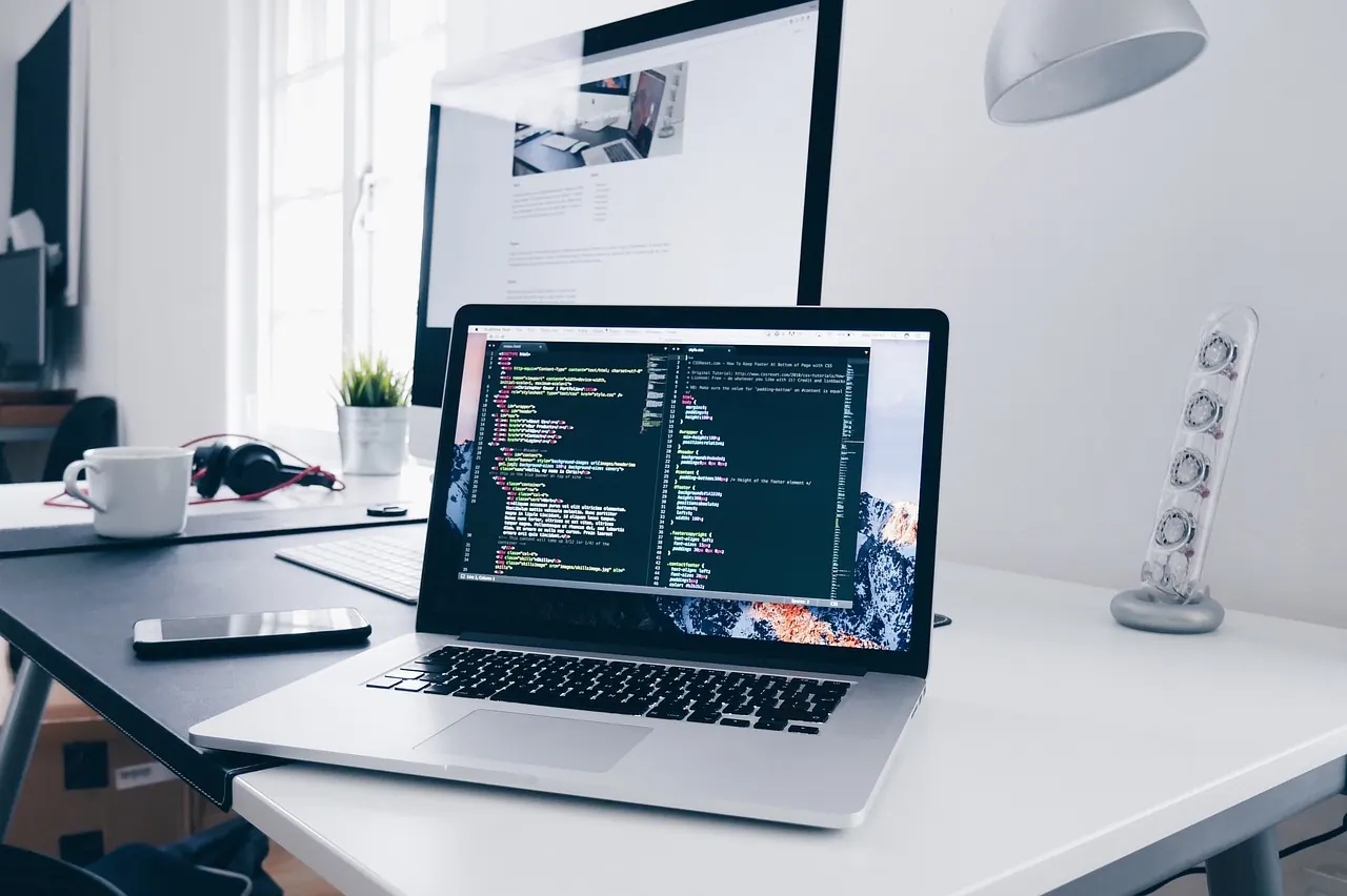 Bàn làm việc với laptop và màn hình hiển thị mã phần mềm