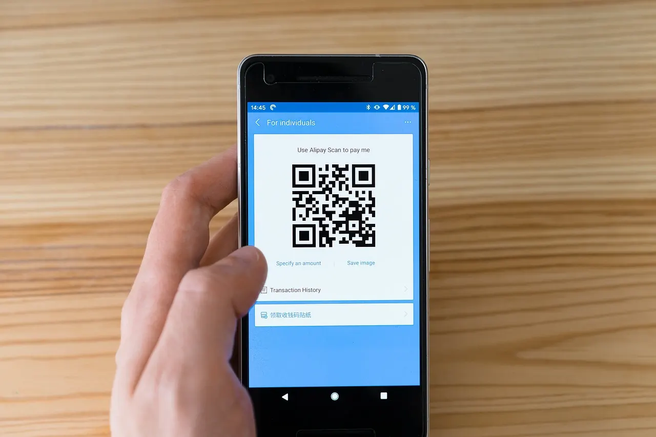Bàn tay giơ điện thoại hiển thị mã QR để quét
