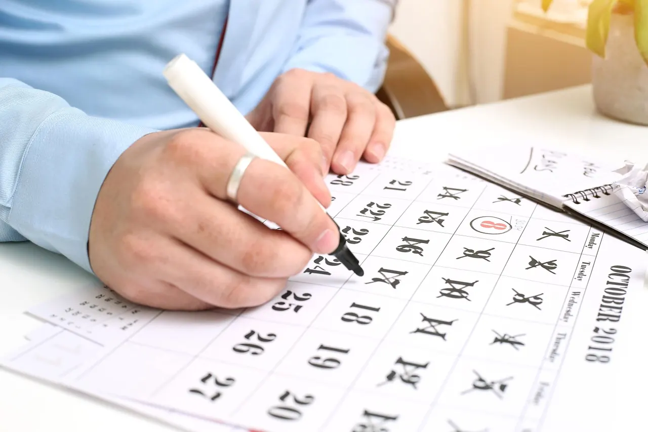 Bàn tay ghi chú lên tờ lịch kế hoạch