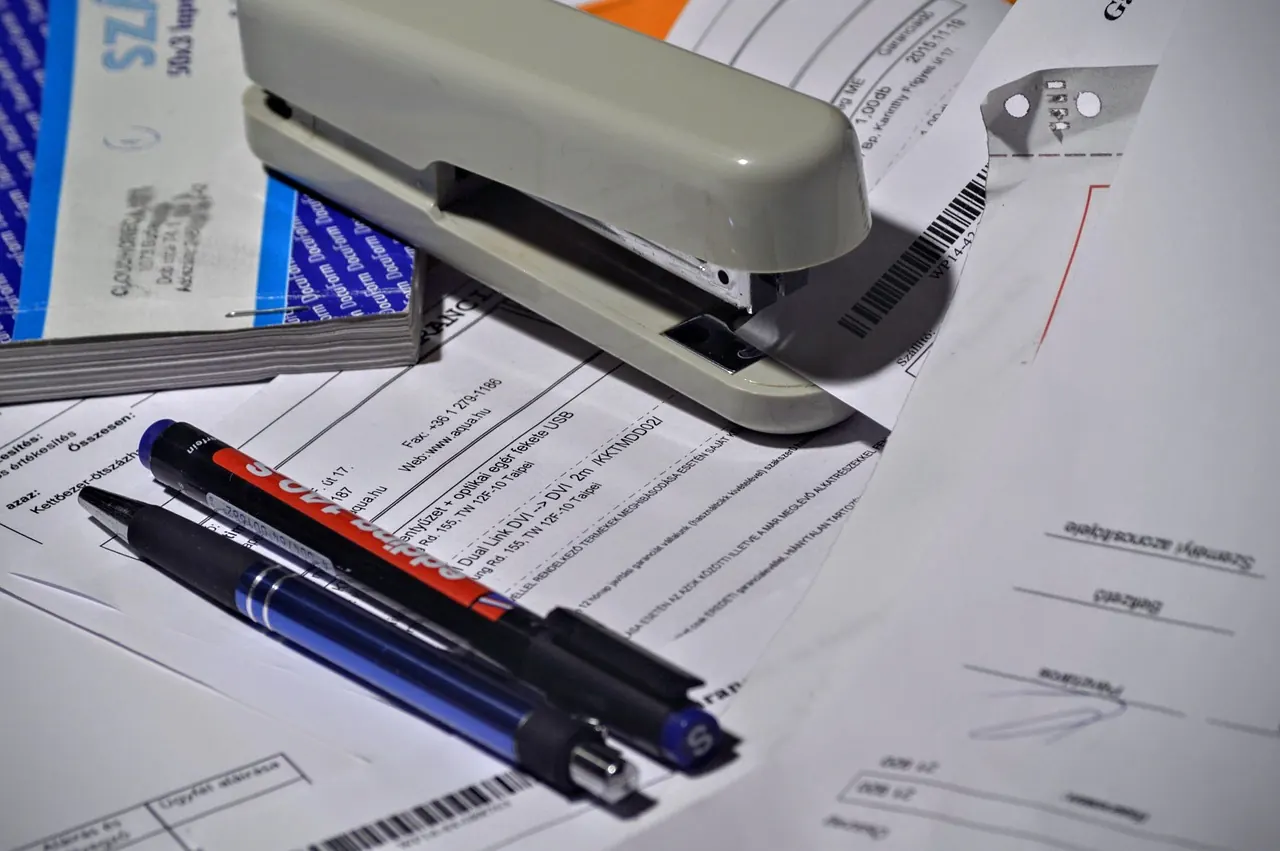 Dập ghim, bút và giấy tờ văn phòng xếp trên bàn