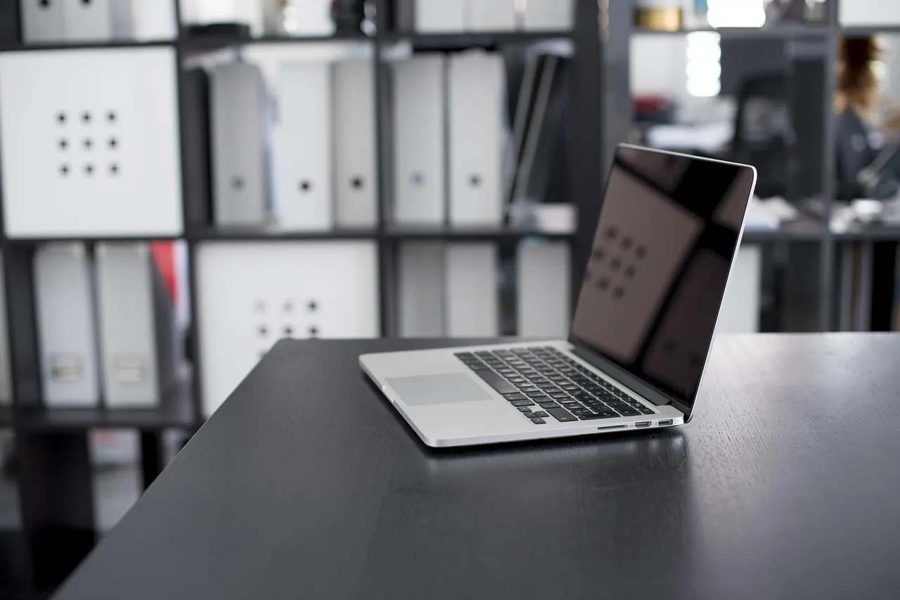 Laptop trên bàn tối cạnh kệ bìa hồ sơ